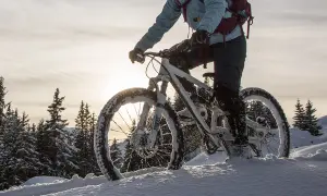 Rowerzysta w zimowym krajobrazie, z rowerem wyposażonym w opony zimowe do roweru, pokonuje zasypaną śniegiem trasę.