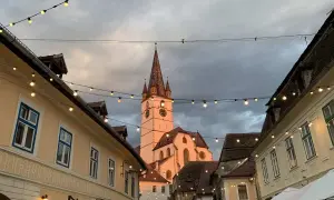 En charmig europeisk stad med en kyrktorn i bakgrunden, kantad av hus och ljusslingor. Perfekt för en resa till billigaste landet i Europa.