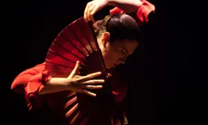 Bailarina de flamenco con un abanico rojo, evocando la pasión de la guajira.