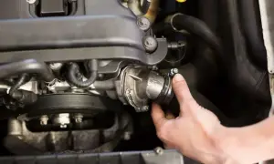 Ręka mechanika dokręca obejmę na wężu układu chłodzenia. To kluczowy etap, by sprawdzić szczelność chłodnicy EGR.
