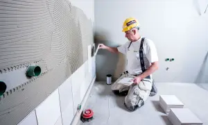 En kakelsättare med hjälm applicerar kakel med kakelfix utomhus.