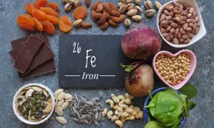 Una tavola ricca di alimenti ricchi di ferro: cioccolato fondente, albicocche, mandorle, pistacchi, barbabietole, fagioli, soia, spinaci, semi di zucca e girasole.