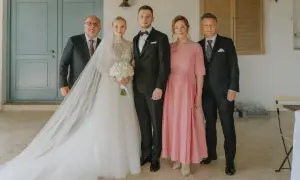 Para weselna z rodzicami. Panna młoda w sukni z welonem, pan młody w garniturze. Obok nich mama weselna w różowej sukience i ojcowie.