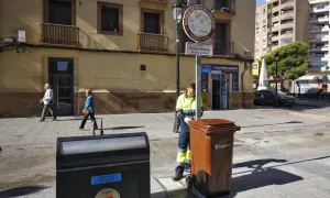 Un trabajador recoge un contenedor marrón en Zaragoza, bajo un sol radiante, como parte de la fiesta del sol.