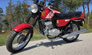 Czerwona Jawa TS 350, jeden z kultowych motocykli, gotowa na przejażdżkę po leśnej drodze.