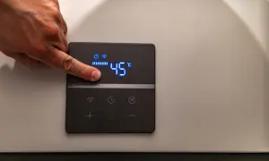 Dito un dito regola la temperatura di 45°C su un pannello di controllo di caldaie elettriche per riscaldamento.