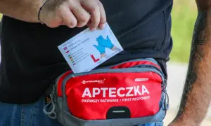Dłoń wyjmuje z apteczki "Pierwszy ratownik" opakowanie rękawiczek nitrylowych.