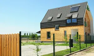 Nowoczesny dom z drewnianą elewacją i panelami słonecznymi na dachu. To ekologiczne rozwiązanie, przypominające trochę earthship, z pewnością przyciąga wzrok.