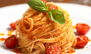Ein Teller mit köstlichen Spaghetti Aglio e Olio, garniert mit frischem Basilikum und Kirschtomaten.