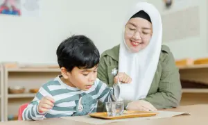 A child practices pouring water in a Montessori classroom, learning practical life skills inspired by nature.