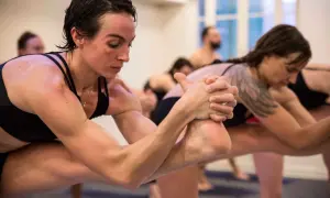 Des pratiquants de hot yoga en pleine concentration, transpirant et étirant leurs corps dans une pièce chauffée.