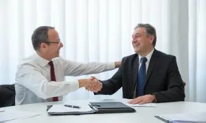 Dos hombres de negocios sonríen y se dan la mano, un ejemplo de escucha activa en una reunión exitosa.