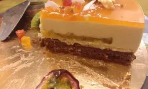 Tranche de gâteau mousseux à l'orange et au fruit de la passion, garnie de fruits et de kiwi.