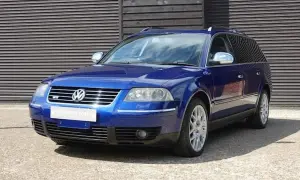 En blå Passat W8 kombi står parkerad framför en träfasad.