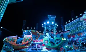 Bunte Fahrgeschäfte und Lichter auf dem Berliner Volksfest. Menschen genießen die Nacht auf dem "Break Dance".