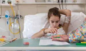 Niña en cama de hospital, con vía intravenosa, jugando con bloques. Un intento de combatir el síndrome de hospitalismo.