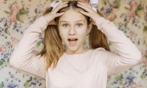 Dziewczynka z kucykami i kokardkami, z otwartymi ustami, może mieć objawy ADHD.