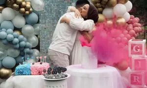 Para świętuje płeć dziecka. Różowy dym unosi się, a balony w kolorach niebieskim i różowym sugerują balon chłopiec czy dziewczynka.