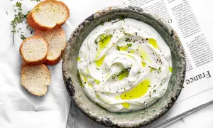 Labneh co to? Kremowy serek jogurtowy z oliwą, pieprzem i tymiankiem, podany z chrupiącymi grzankami. Idealny na śniadanie lub przekąskę.