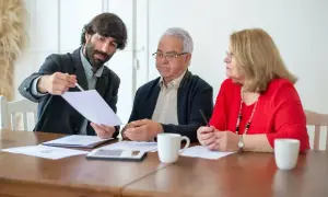 Mężczyzna w garniturze tłumaczy starszej parze dokumenty, omawiając potencjalne wady umowy dożywocia.