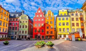 Kolorowe kamienice na placu w Gamla Stan, Sztokholm, pod błękitnym niebem z chmurami.