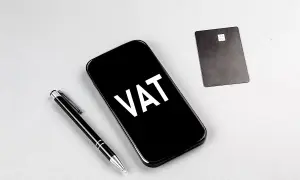 Telefon z napisem VAT, obok długopis i karta płatnicza. Ułatwia to ptu rejestracja.