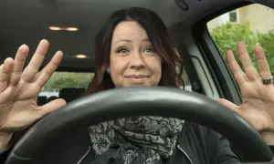 Kvinna visar hur man ska hålla ratten med båda händerna, redo att köra.