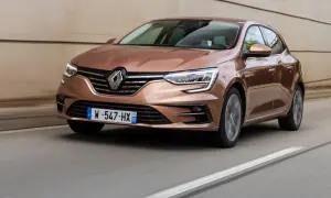 Brązowy Renault Megane RS 4 pędzi po drodze, jego reflektory ostro świecą.