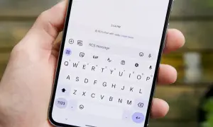 Dłoń trzyma smartfon z otwartą klawiaturą. Na ekranie widać informację "RCS chat with Judy", co wyjaśnia, rcs co to jest.