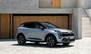 Srebrny Kia Sportage GT Line z czarnym dachem zaparkowany przed nowoczesnym budynkiem z drewnianymi drzwiami i betonowymi schodami.