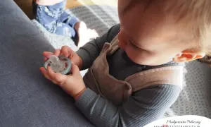 Dziecko bawi się smoczkiem, co może być pierwszym krokiem, jak odzwyczaić dziecko od smoczka.