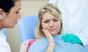 Kobieta cierpi na ból zęba po zatruciu. Dentysta i asystentka próbują jej pomóc.