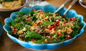 En stor blå skål fylld med ett färgglatt tabbouleh recept med bulgur, tomater, lök och färska örter.