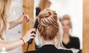 Fryzjerka stylizuje eleganckie upięcie. Zastanawiasz się, ile zarabia fryzjer? To zależy od wielu czynników, ale umiejętności i doświadczenie są kluczowe.