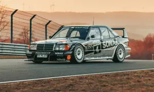 Czarny Mercedes 190 Evo na torze wyścigowym, z licznymi sponsorami na karoserii, gotowy do startu.