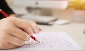 Dłoń z ołówkiem zaznacza odpowiedzi na arkuszu. Zastanawiasz się, ile trzeba mieć procent z egzaminu zawodowego żeby zdać?