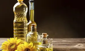 Bottiglie di olio di semi e girasoli. Si può mischiare l'olio d'oliva con l'olio di semi per un sapore unico.