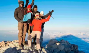 Grupa przyjaciół na szczycie wulkanu Teide, ciesząca się widokiem. Wejście na wulkan Teide zajmuje kilka godzin i wymaga zezwolenia.