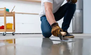 Pose d'un béton ciré lisse, parfait pour un chauffage au sol. Un artisan applique la matière avec une taloche.