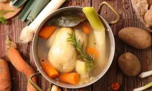 Un plat mijoté de poule au pot, avec carottes, poireaux et pommes de terre, prêt à être dégusté.