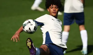 Młody piłkarz, niczym cr7 jr., trenuje na boisku, wykonując efektowne kopnięcie.