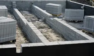 Budowa fundamentów z bloczków betonowych, przygotowanie pod ocieplenie fundamentów. Materiały budowlane czekają na użycie.