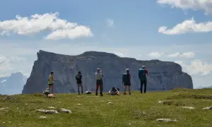 Groupe de randonneurs admirant un impressionnant plateau rocheux lors d'un trek dans le Vercors. Ciel bleu et nuages blancs.