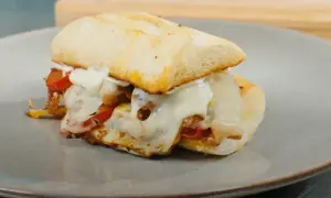 En saftig philly steak sandwich med smält ost och paprika på en tallrik.