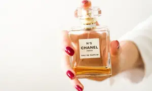 Dłoń z czerwonymi paznokciami trzyma flakon Chanel N°5. Czy perfumy mają datę ważności?