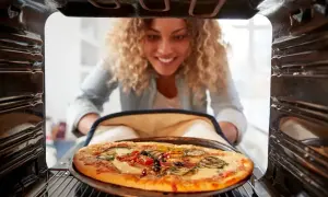 Kobieta wyjmuje z piekarnika pyszną pizzę. Idealna temperatura do pieczenia pizzy to klucz do sukcesu.