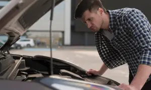 Mężczyzna pochyla się nad otwartą maską Hyundai i20, przygotowując się do wymiany żarówki mijania.