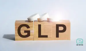 Drewniane klocki z literami GLP i tabletki symbolizujące leczenie.
