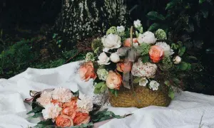 Dwa bukiety delikatnych kwiatów, jeden w wiklinowym koszu, drugi na białym materiale. Piękna fotografia kwiatów.
