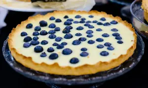Pyszna tarta z borówkami, z kremowym nadzieniem i chrupiącym spodem, prezentuje się apetycznie na szklanej paterze.